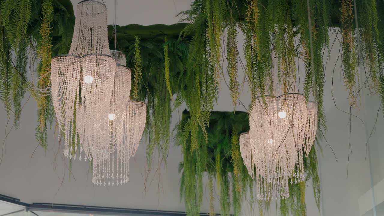 Elegant Crystal Chandeliers and Lush Greenery Hanging from the Ceiling