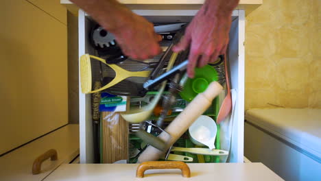 Top-down-view-as-hands-open-kitchen-draw,-search-through-mess-of-utensils-and-then-close-draw