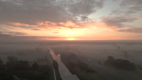 sunrise over foggy landscape with canal and highway