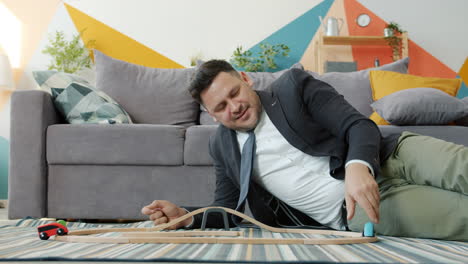 businessman playing with toy cars at home