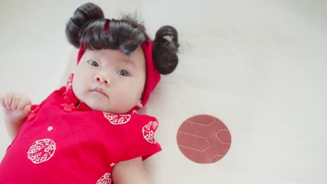 portrait cute asian newborn baby infant girl in chinese traditional red costume, concept of holidays chinese new year