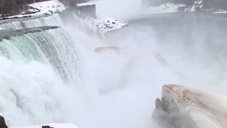 la cámara mira hacia las cataratas del niágara con un gran trozo de hielo en primer plano