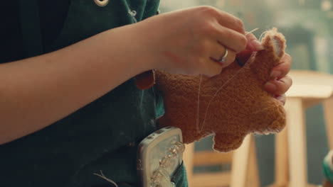 woman sewing a stuffed animal