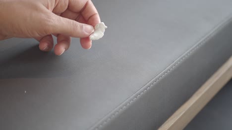 hand picking up chewing gum from a grey surface