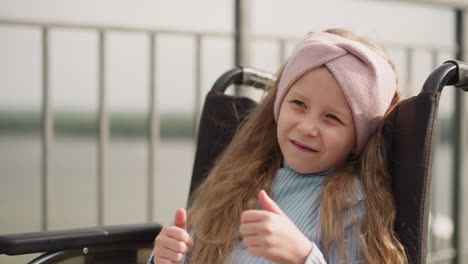 little girl turns to camera trying to show thumb up gestures