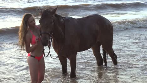 mujer en bikini con caballo en la playa