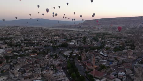 panoramic aerial dolly at dusk over stunning urban town of cappadocia turkey with hot air ballons in sky