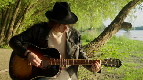 man playing acoustic guitar by the river