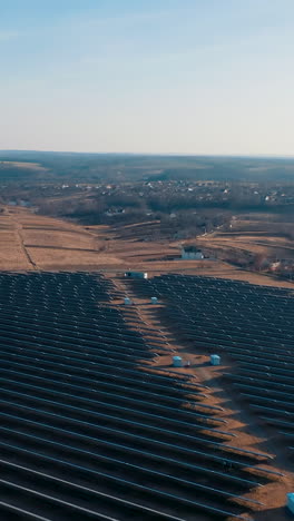 aerial view of solar power station panels. autumn landscape at sunset with fields, houses, forests and solar panels. vertical video