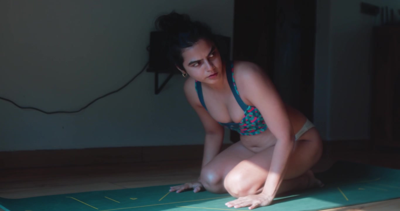 Giovane donna termina un plank sugli avambracci su un tappetino da yoga a casa, abbassa le ginocchia e si siede indietro per recuperare dopo l'esercizio