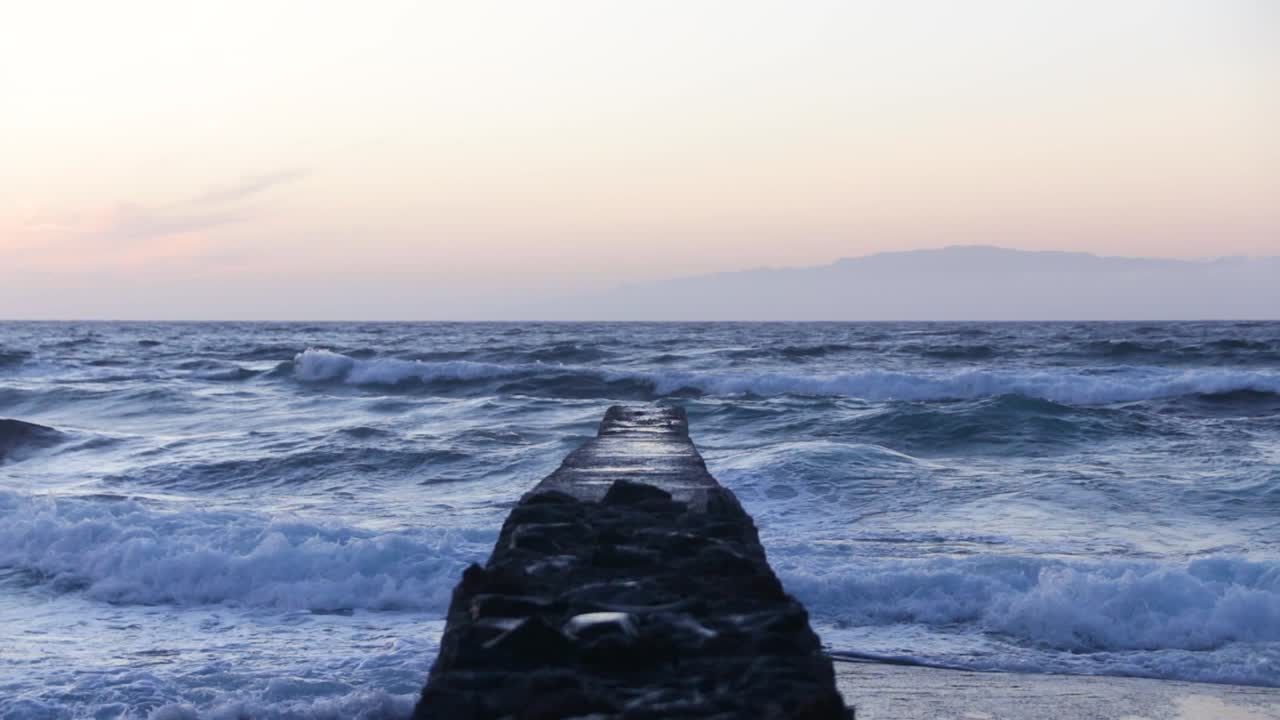 Starke Wellen schlagen gegen eine Mauer, die gebaut wurde, um die Wellen abzuwehren, Playa de Las Américas, Teneriffa