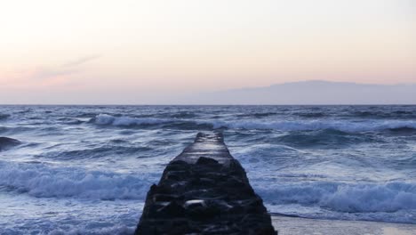 strong waves crashing into a wall that was built to stop the waves, playa de las americas, tenerife