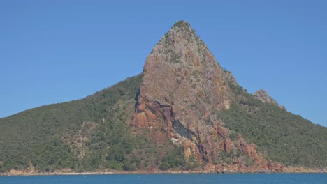 rocky peak of pentecost island against blue sky - scenic island with seascape in whitsunday, qld, australia