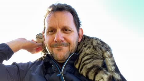 Lovely-cat-on-mans-shoulders-Feels-well-during-the-sunset,close-up-shot