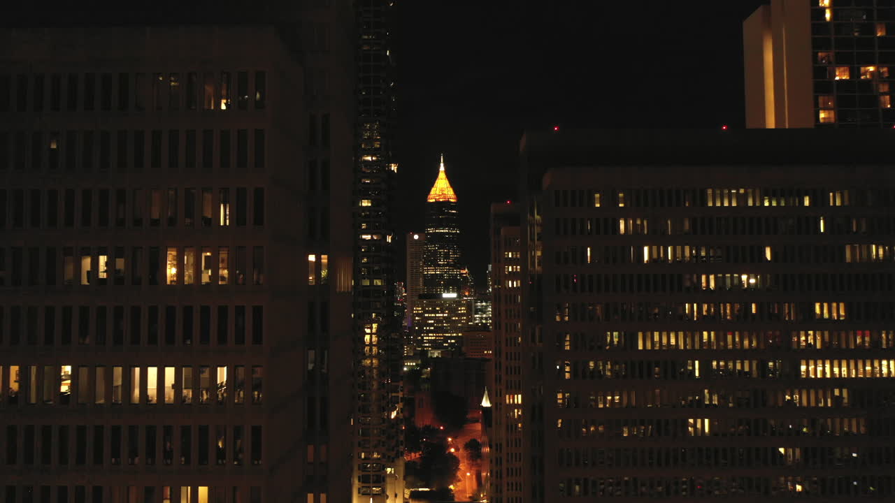 Riprese drone di un grattacielo di Atlanta di notte tra gli edifici, nel centro città, con zoom in.