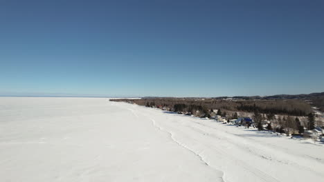 Drones-Voladores-Sobre-Casas-Y-Un-Lago-Congelado-Durante-El-Invierno-En-Canadá