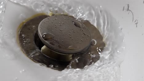 water draining down bathroom sink drain close up