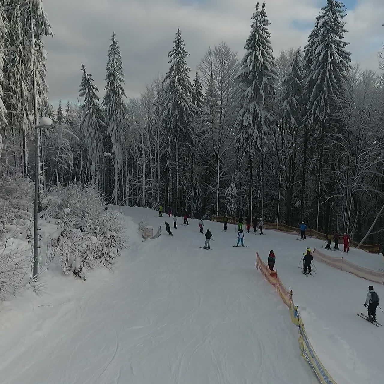 Sciatori e snowboarder scendono su una pista da sci in una località di montagna sullo sfondo di un inverno nevoso.