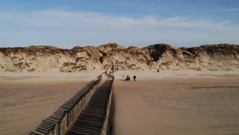 Touristen-Am-Sandstrand-Mit-Einer-Reihe-Von-Holzpfählen-Im-Sommer-In-Brouwersdam,-Niederlande