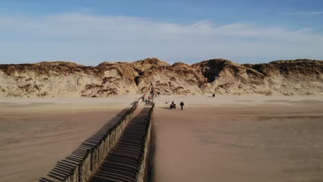 tourists on sandy shore with row of wooden piles at summertime in brouwersdam, netherlands