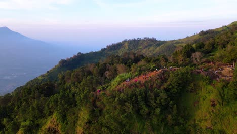 People-standing-at-Sikunir-viewpoint-to-the-jungle-in-Central-Java-at-sunset,-Indonesia