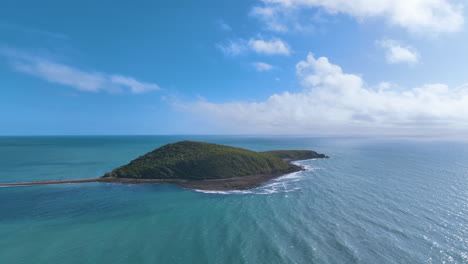 Aerial-approaches-sub-tropical-island-off-Queensland's-coast-revealing-reef,-beach,-rocky-shore-and-fertile-forested-hill-slopes