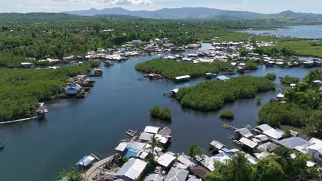 Day-Asan-floating-village-in-Surigao-Del-Norte,-Philippines-showing-lush-greenery-and-metal-roofed-houses