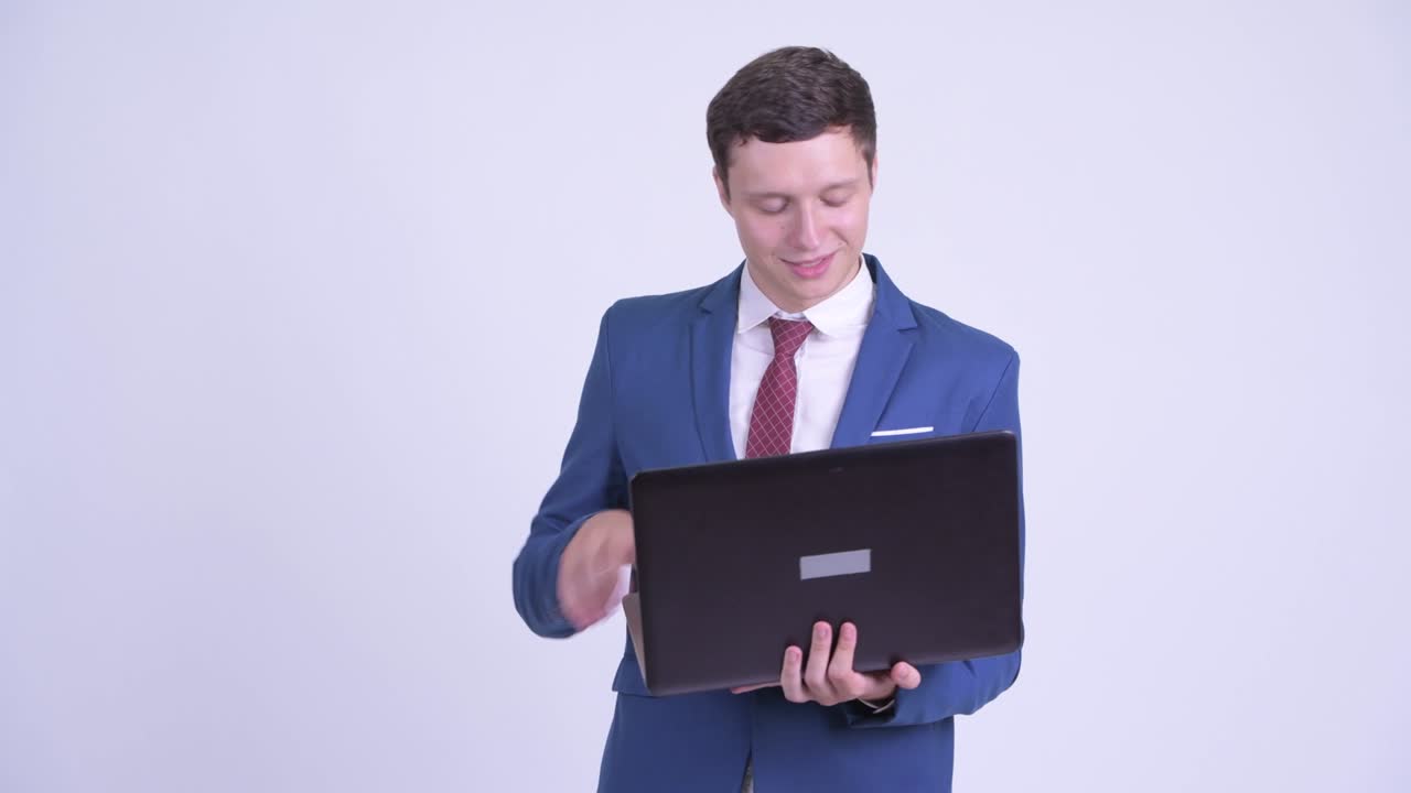 feliz joven hombre de negocios guapo en traje con computadora portátil