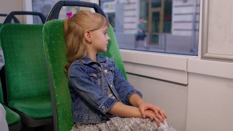 Portrait-of-child-girl-passenger-riding-at-public-modern-bus-or-tram-transport,-looking-out-window