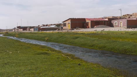 Ländliches-Bolivianisches-Dorf-Mit-Bach-Und-Leuchtend-Grünem-Gras,-Unter-Klarem-Himmel,-Ruhige-Atmosphäre