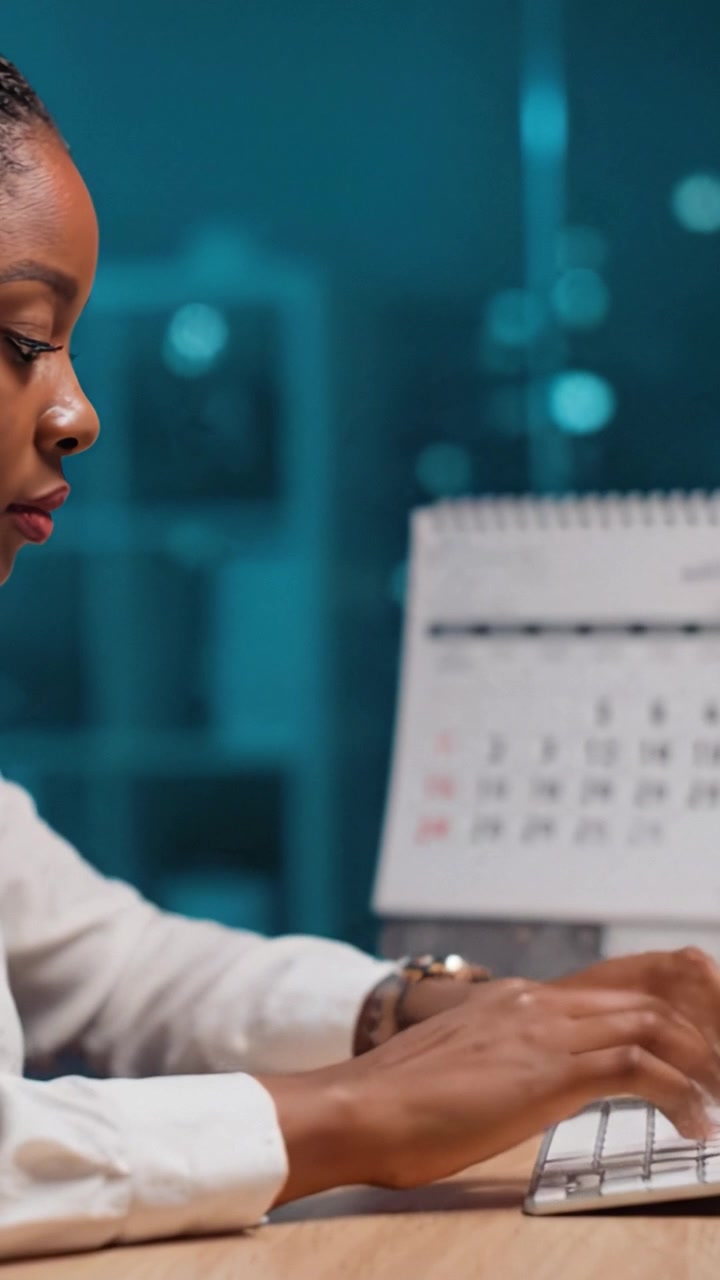 Focused Individual Working at Desk with Calendar in the Background, Typing on Keyboard, Surrounded by a Calm and Productive Evening Environment