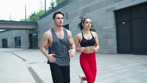 fitness couple running on urban street together