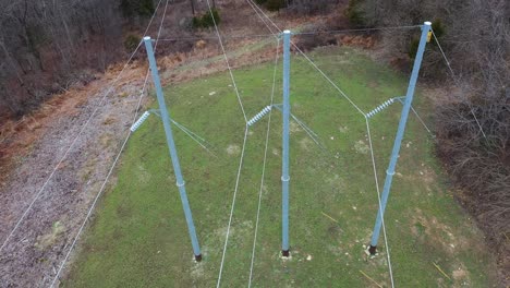 Aerial orbit of 3 steel electrical transmission structures in Frankfort Kentucky KU towers with massive new ceramic bell insulators and high voltage conductors