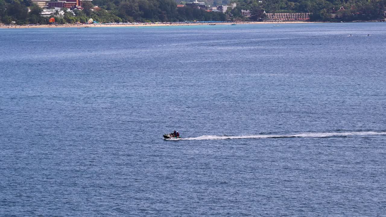 A jet ski glides swiftly across the ocean in Phuket, Thailand, under clear skies, capturing a sense of freedom and adventure