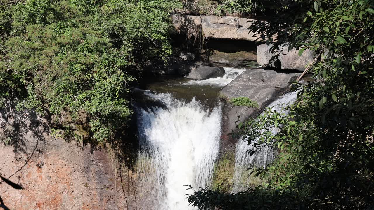 el agua cae en cascada por las rocas en medio de la vegetación