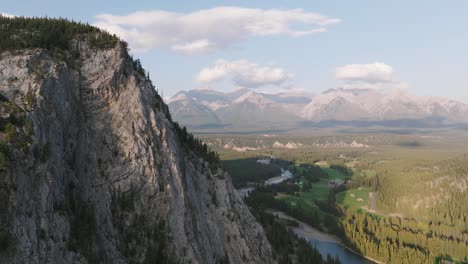 Aerial-dolly-in-near-steep-hill-revealing-pine-tree-forest-and-Bow-River-at-Banff-National-Park,-Canadian-Rockies,-Alberta,-Canada