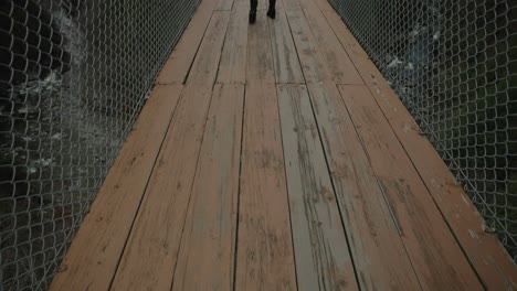 vista trasera de una mujer milenaria en un puente suspendido disfrutando de un viaje en solitario durante el invierno en coaticook, quebec, canadá, vista trasera, cámara lenta
