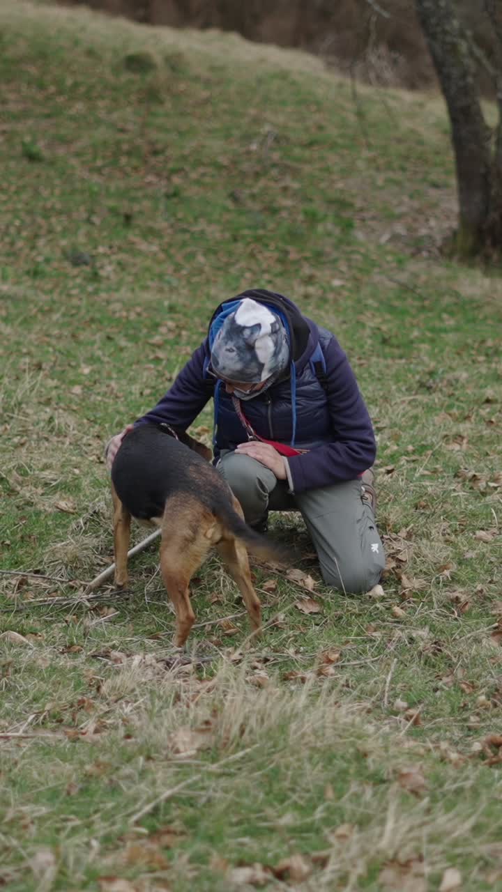 A woman interacting with her dog in a grassy field