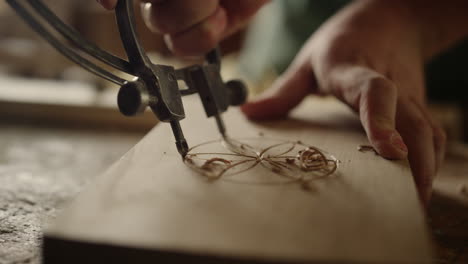 man carving ornament in wood indoors