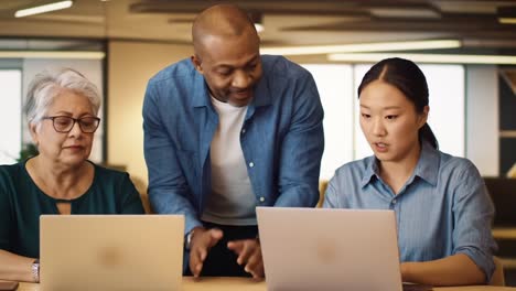 collaborative innovation: a diverse team engages in problem-solving at work using laptops in a modern office environment