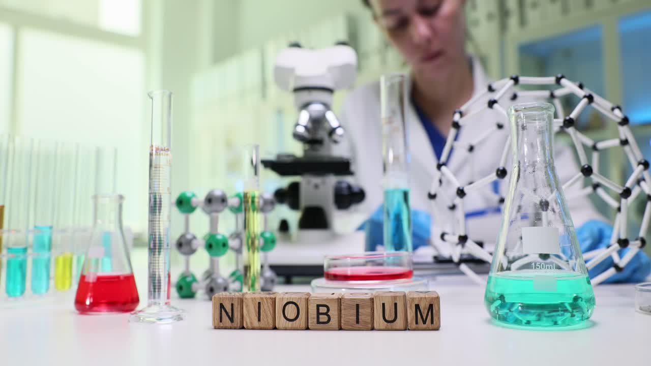 Scientist in a lab with Niobium spelled out, surrounded by chemical equipment