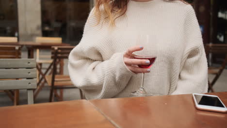 레드 와인 한 잔을 마시며 카페에 앉아 있는 어린 소녀