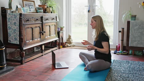 a woman doing yoga in a room with a laptop