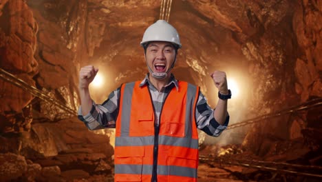 asian male engineer with safety helmet screaming goal celebrating working in underground mine tunnel