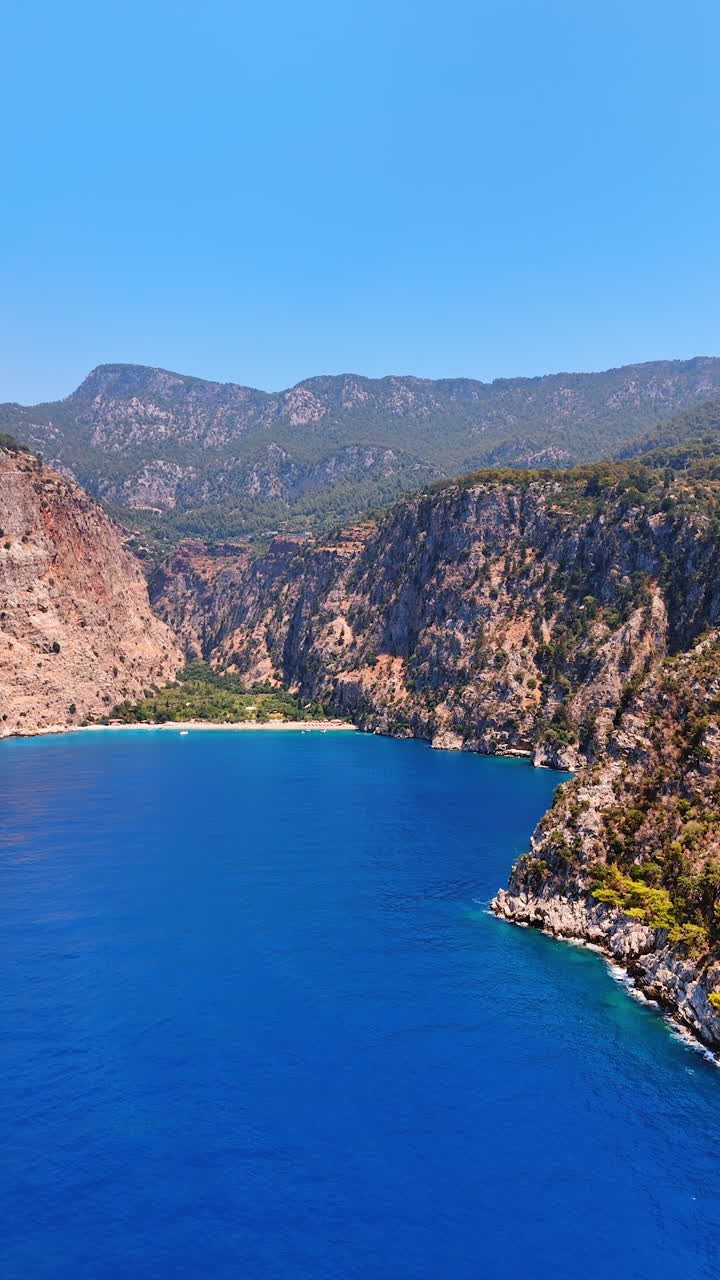 Stunning coastal view in a rocky bay. Bright blue waters and rocky cliffs create a serene coastal scene, ideal for relaxation and exploration