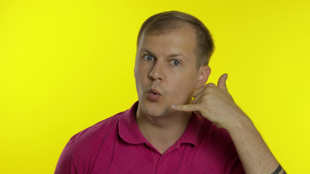retrato de un hombre posando en una camiseta rosa. un tipo feliz pidiéndole que lo llame, muestra el teléfono con la mano