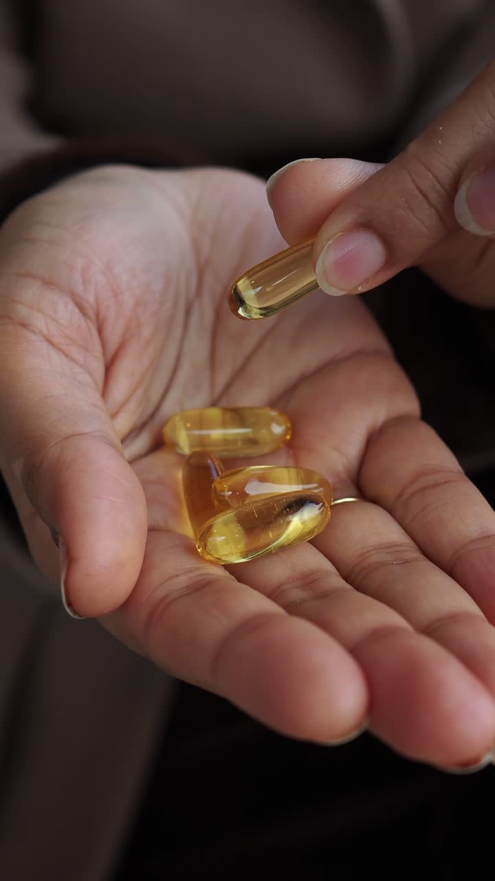 Primo piano di una mano che raccoglie una capsula di gel gialla