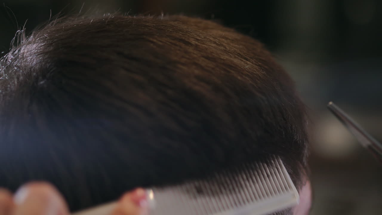 Close-up, master hairdresser does hairstyle and style with scissors and comb. Concept Barbershop.