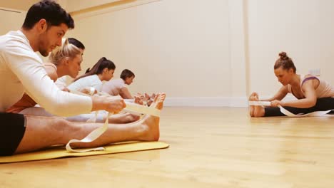 trainer helping group of people with stretching exercise