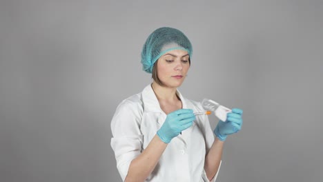 young female doctor in gloves holding a syringe isolated on grey background. healthcare concept. shot in 4k